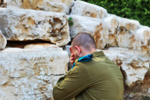 Israeli soldier crying in front of the graves of fallen soldiers. Concept: Israeli soldiers, Israel Memorial Day – Yom HaZikaron, Holocaust Remembrance Day – Yom hashoah, Israel Independence Day