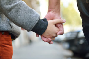 Hands of mother and child outdoor closeup. Mother holds hand of