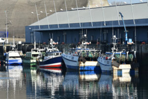 A colorful fleet of docked fishing boats with reflections in calm water of the fishing harbor of Keroman, Lorient, Britanny France