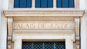 Gros plan de l’enseigne écrite au fronton de la façade du palais de justice de Paris, France, avec les mots « Palais de Justice » écrits en Français en lettres dorées