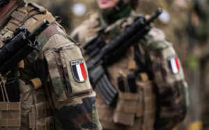 France Army soldiers uniform. Close up photo with the France flag on a military soldier uniform with the gun next to it. Military industry concept photo.