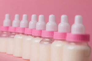 Baby bottle full of milk on a pink background