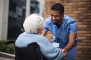 Senior woman at wheelchair spending time outside with her assistant.