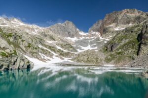 View of the turquoise waters of Lac Blanc reflecting the snow-capped peaks of the Mont Blanc massif under a clear blue sky in Chamonix, Auvergne-Rhone